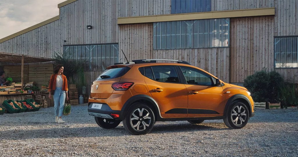 Dacia Sandero Stepway crossover parkerad framför en gårdsbutik.